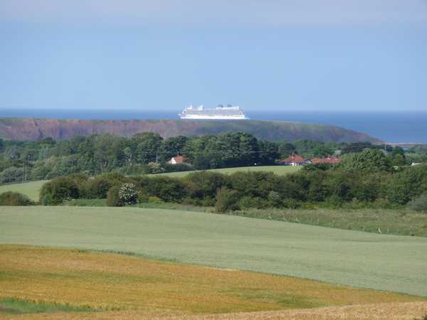 A huge cruise ship passes behind Filey Brigg